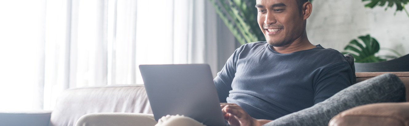 Man sits on couch with his laptop.